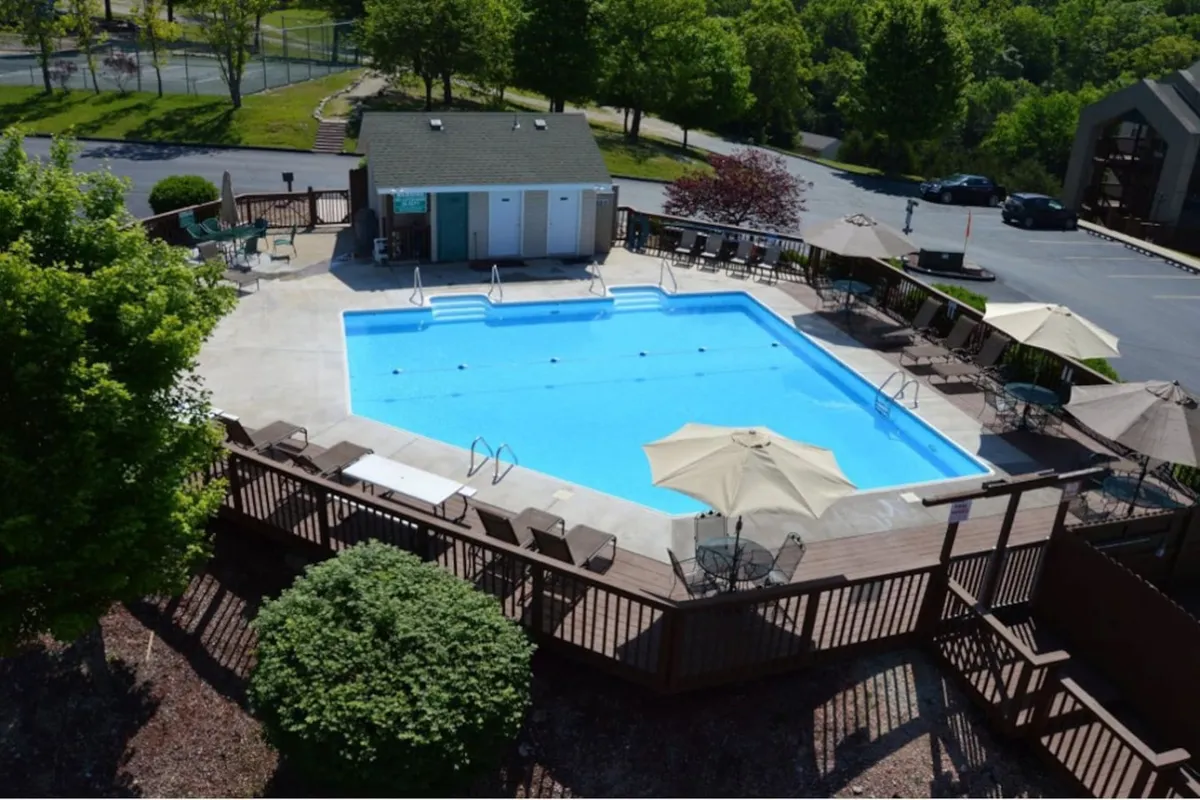 A sparkling swimming pool with lounge chairs, umbrellas, and poolside changing rooms create a relaxing, social setting for all ages. The open layout and welcoming vibe evoke leisure time spent unwinding after a day of adventure.