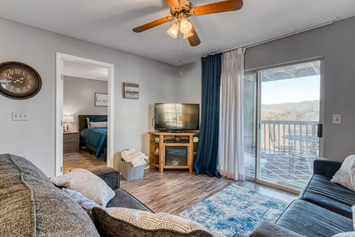 A cozy living room scene with a soft sofa, a television for movie nights, a window providing ample natural light, and a clock on the wall. The space feels inviting and relaxed, ideal for unwinding after a busy day.