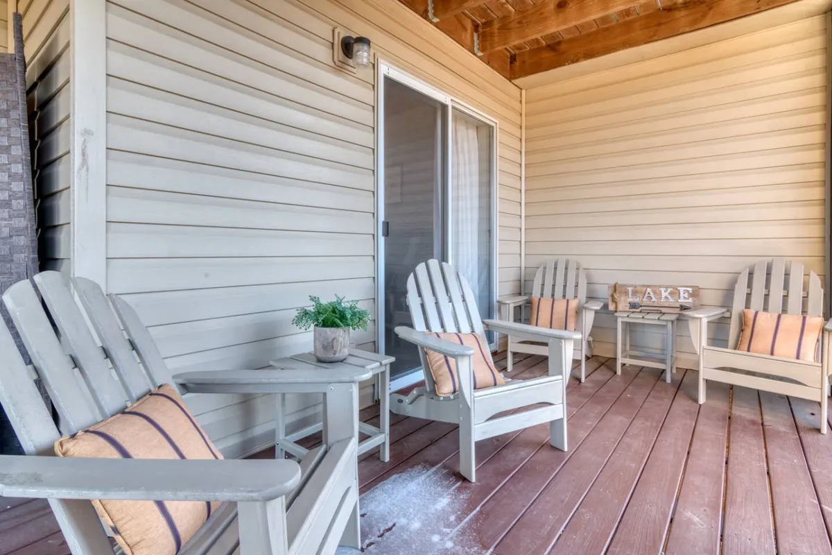 A peaceful outdoor seating area with wooden chairs, potted plants, and a sign that says 'LAKE' in the background. The setting faces the lake, inviting guests to sit, relax, and soak in the tranquil views.