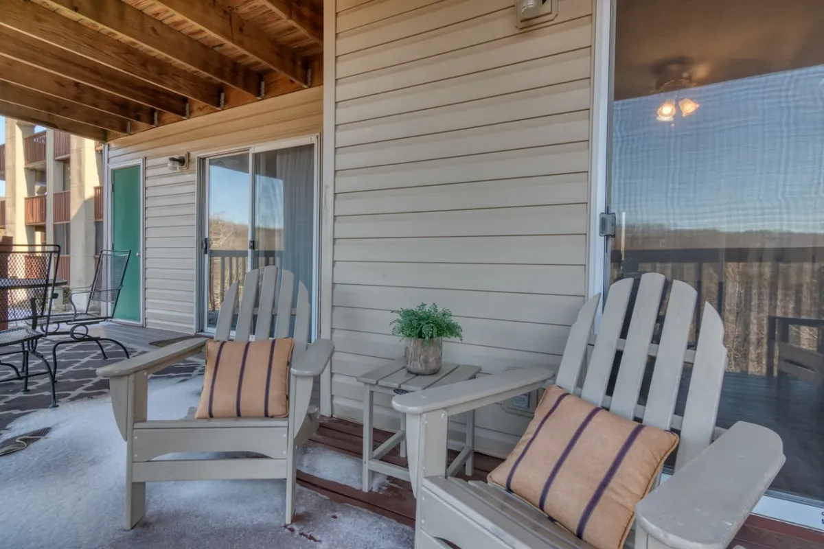 A cozy outdoor patio with Adirondack chairs and a small table, set against sliding glass doors that connect inside and outside. The space is perfect for relaxing, sharing drinks, and enjoying the evening air after a night out or before heading to local attractions.
