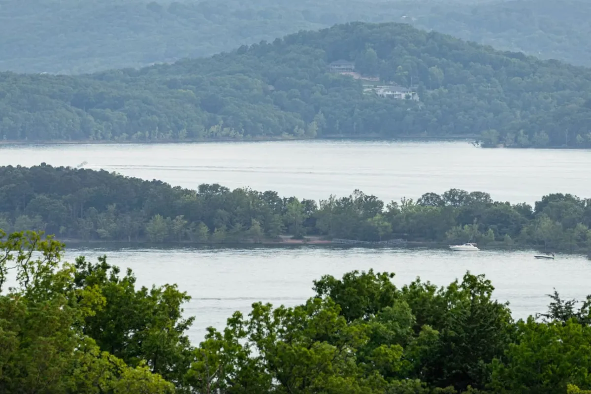 A panoramic view of a tranquil lake surrounded by mountains and trees, hinting at peaceful moments spent outdoors. The calm water and natural landscape evoke a sense of relaxation and provide context for year-round lake access.